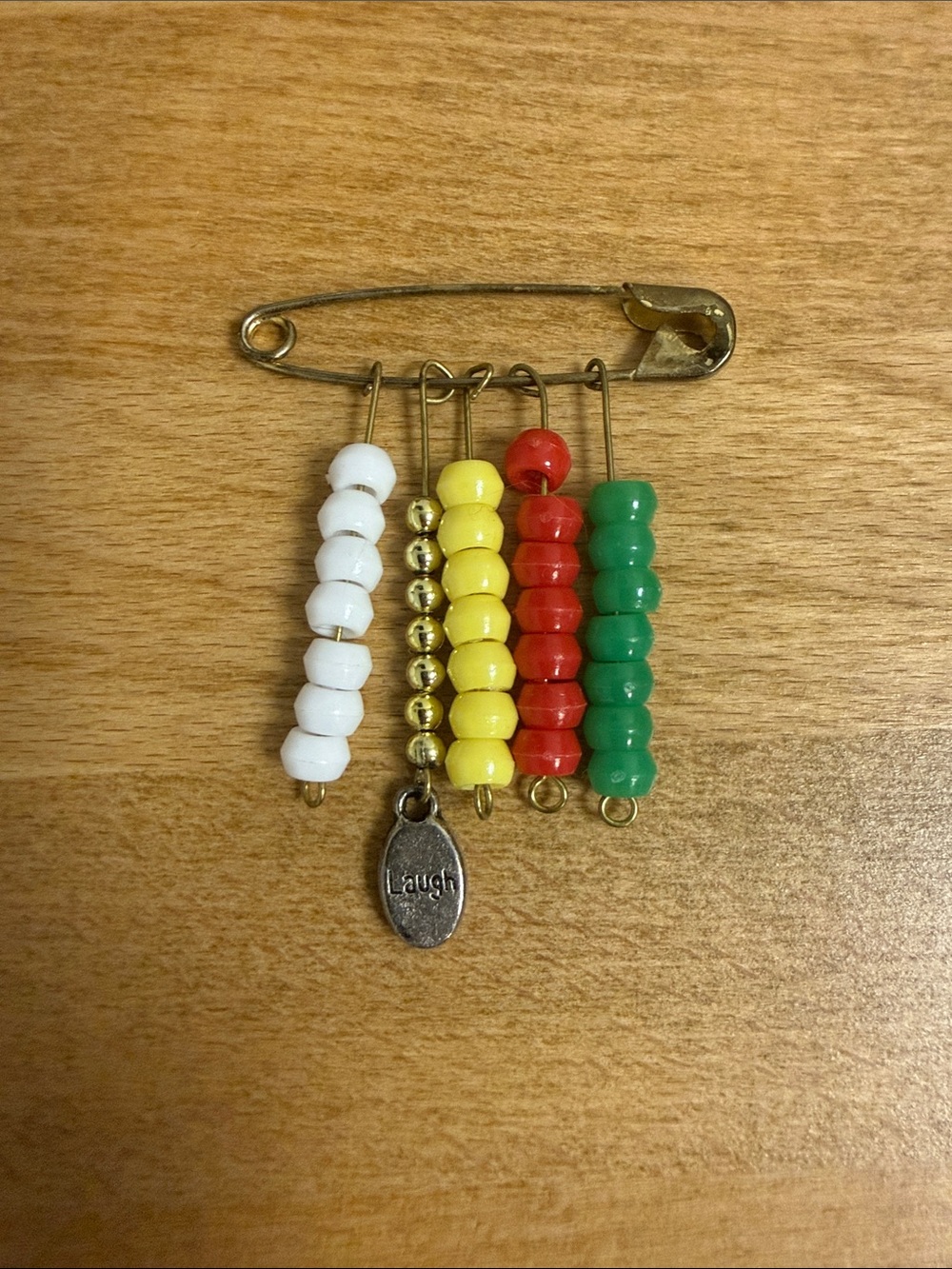 Beaded safety pin lapel with laugh charm in African colors